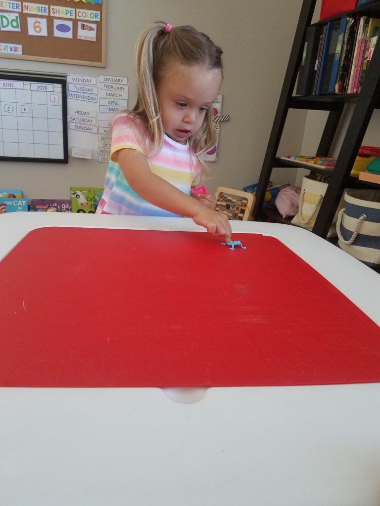 toddler girl playing with toy jumping frogs for preschool activity