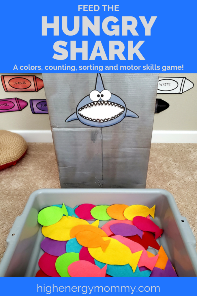 Pinterest pin for Preschool ocean theme game made with a grey paper shark face glued onto a large cardboard box with mouth cut out and plastic bin of colorful felt fabric fish