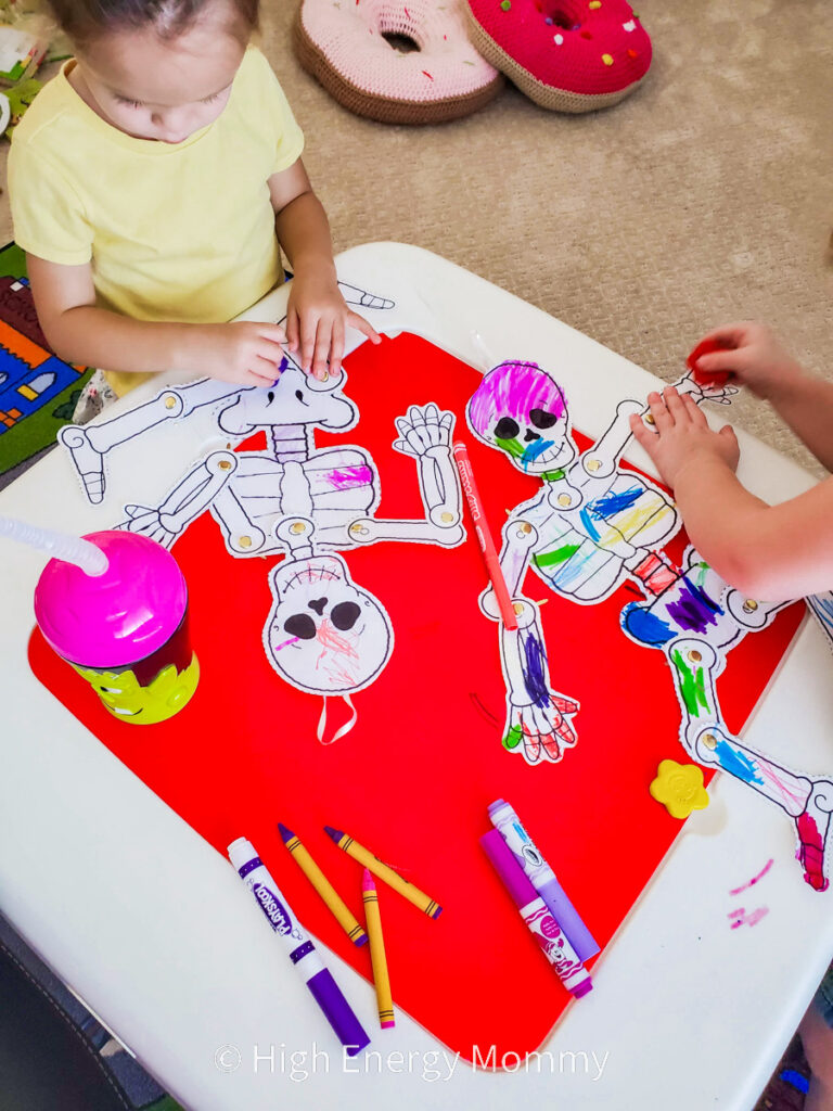 two kids coloring and assembling a paper skeleton