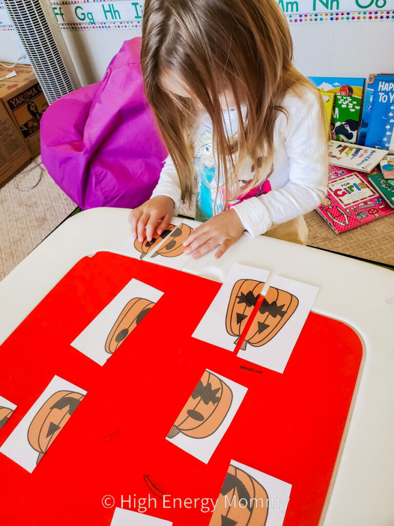 toddler girl matching up pumpkin face cards