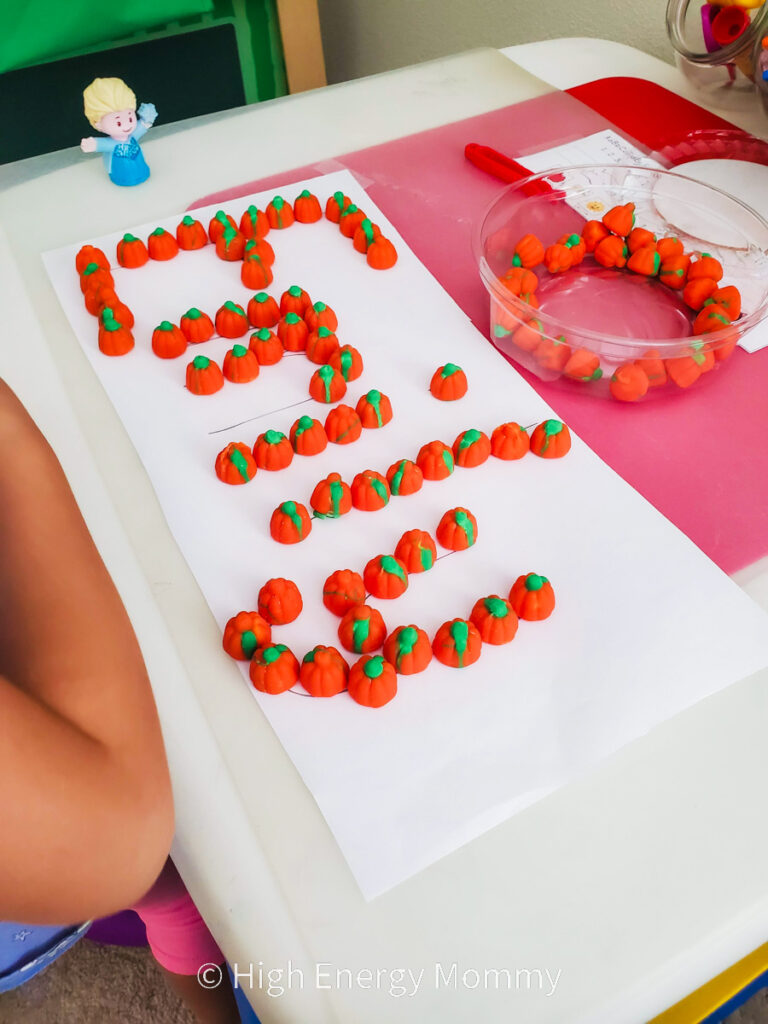 white piece of paper with the name Emily outlined with candy pumpkins