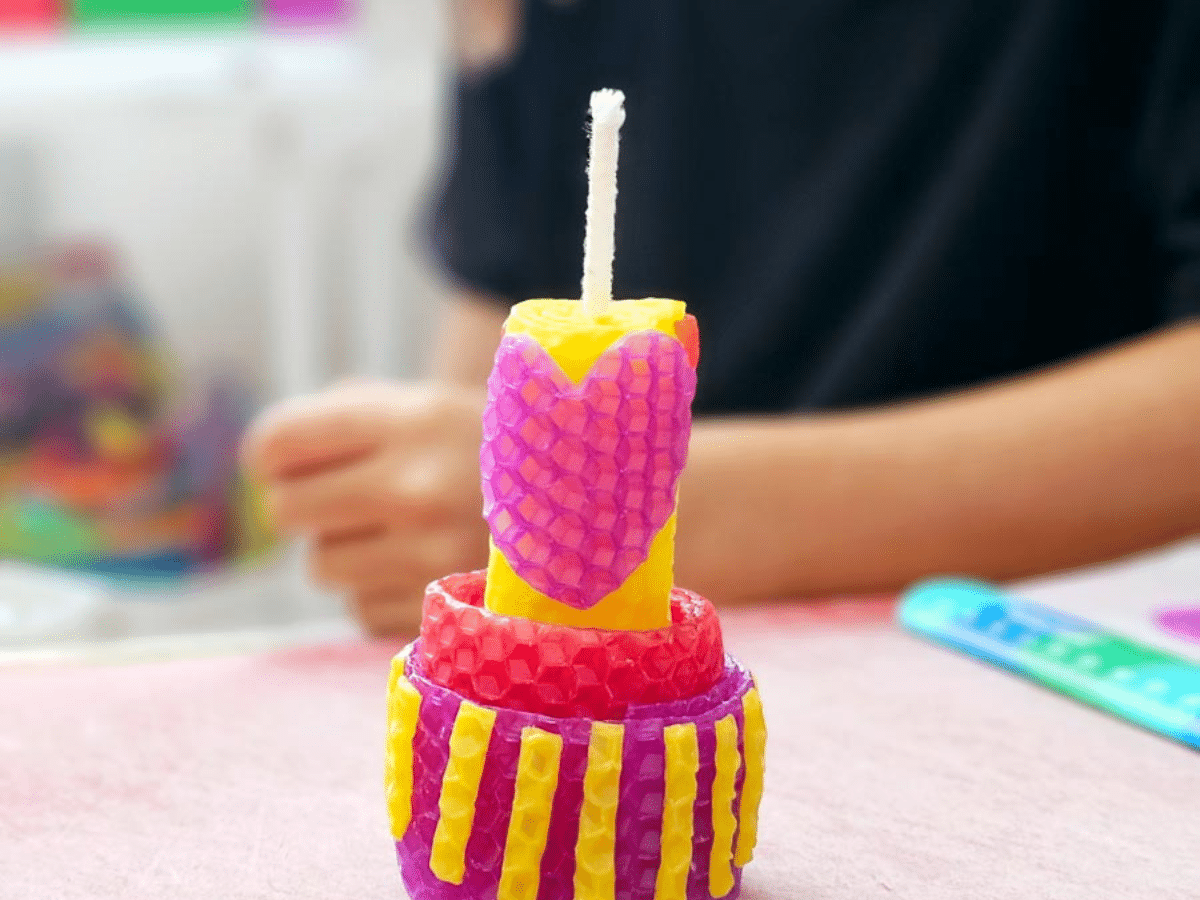 Homemade beeswax candle that is yellow and pink with a heart