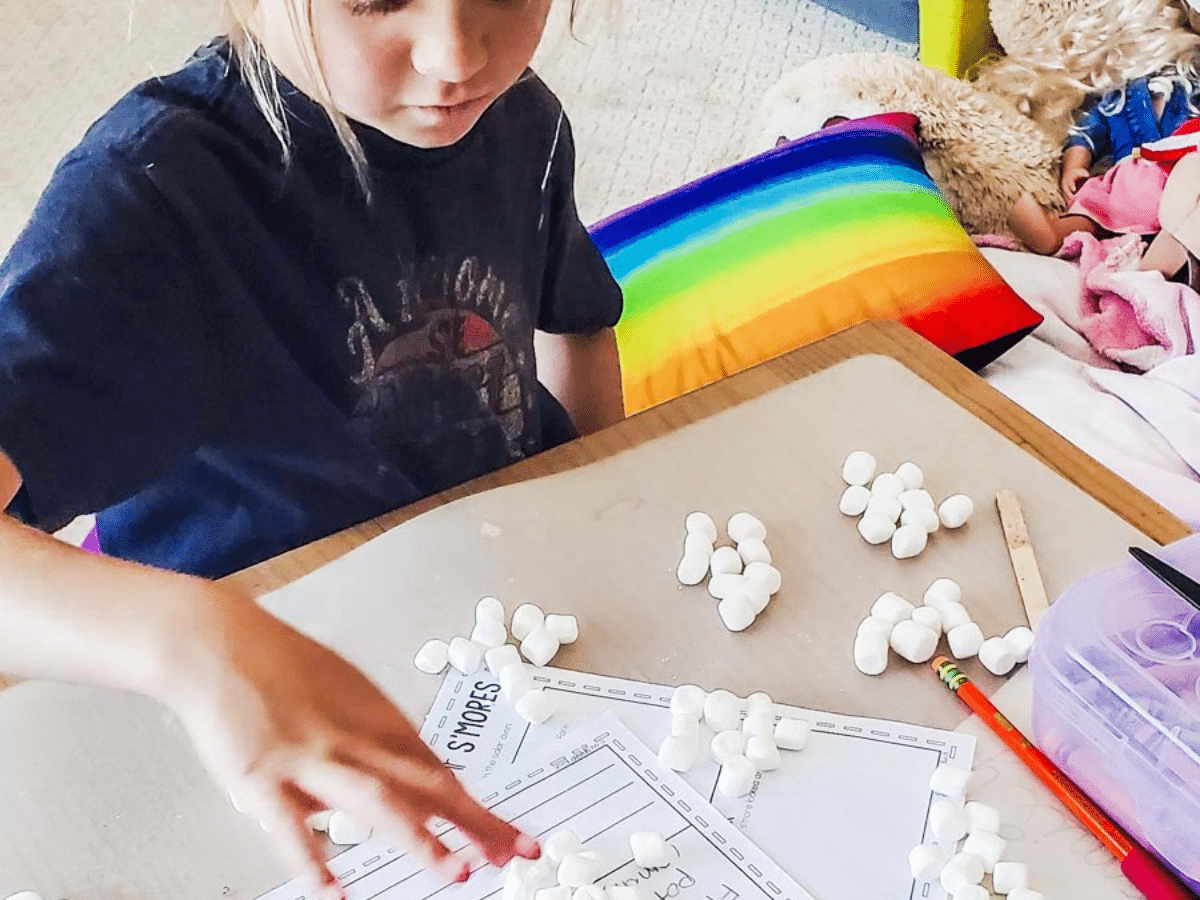 Child counting sets of marshmallows on a school desk
